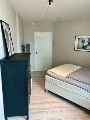 a bedroom with a bed and a dresser with a mirror at Lys og moderne 3-roms på Sandsli in Bergen