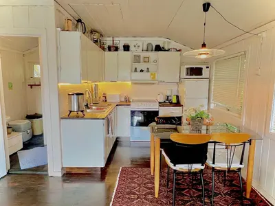 a kitchen with white cabinets and a table and chairs at Cabin at Hestsjøen Badeplass in Trondheim