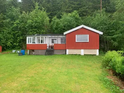 a red and white house in the middle of a yard at Cabin at Hestsjøen Badeplass in Trondheim
