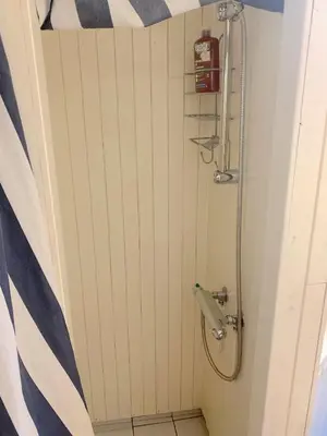a bathroom with a shower with blue and white stripes at Cabin at Hestsjøen Badeplass in Trondheim