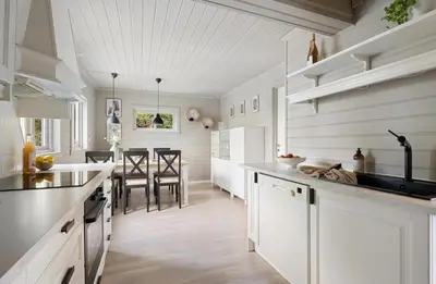 a kitchen with white cabinets and a dining room at Vestlandsidyll ved sjøen & Bergen