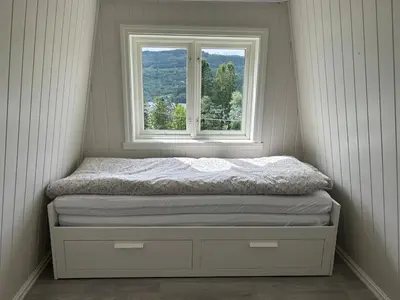 a bed in a room with a window at Vestlandsidyll ved sjøen & Bergen