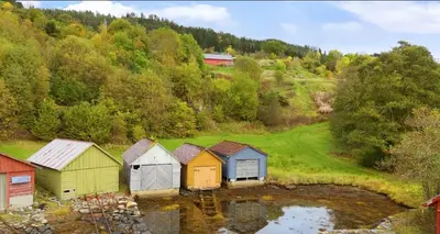 a group of colorful houses on a hill next to a body of water at Vestlandsidyll ved sjøen & Bergen