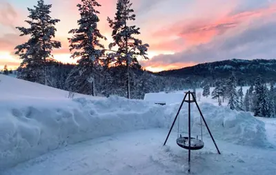 a swing in a pile of snow at sunset at 4 Bedroom Nice Home In Vinje in Trovatn