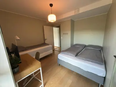 a bedroom with two beds and a table in it at Large luxurious apartment with private terrace and parking in Bergen