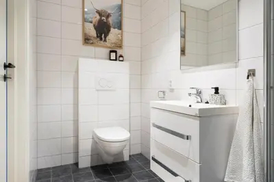 a white bathroom with a toilet and a sink at Large luxurious apartment with private terrace and parking in Bergen