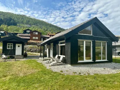 a small black house with a grass yard at Hytte sentralt i Myrkdalen in Vossevangen