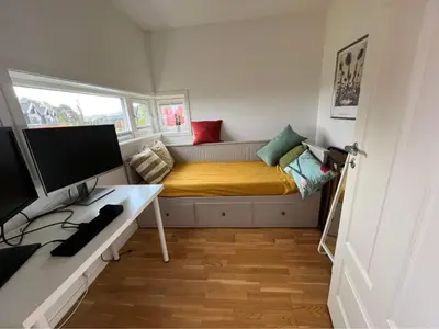 a small room with a bed and a desk with a computer at The house next to the fjord in Trondheim