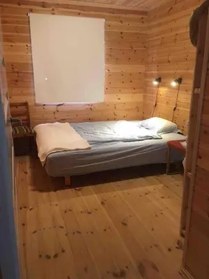 a small bed in a wooden room with a window at Gorgeous views and sunsets in Halsnøy, Kvinnherad in Ådnavik