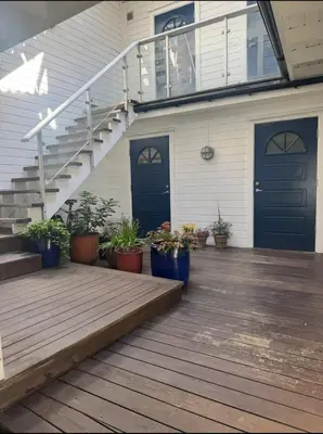 a porch with stairs and blue doors and potted plants at Modern central apartment in a quiet area in Bergen