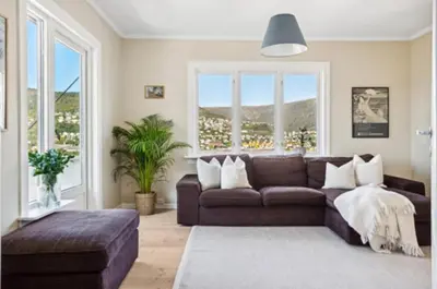 a living room with a brown couch and a large window at Bright apartment with mountain views in Bergen