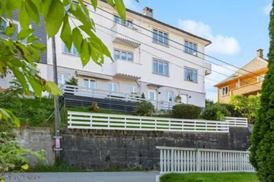 a white house with a white fence in front of it at Bright apartment with mountain views in Bergen
