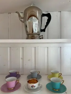 a tea kettle on a shelf with four cups at Historic Cabin By The Atlantic Ocean Road in Vevang