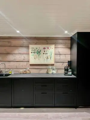 a kitchen with black cabinets and a painting on the wall at Historic Log House At The Foot Of Middagstind in Sæbø