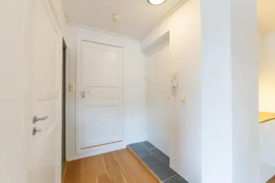 a hallway with a white door and a wooden floor at Unique relaxed corner flat in central Bergen in Bergen
