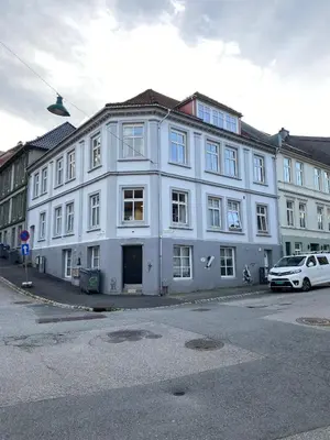 a white building with a car parked in front of it at Unique relaxed corner flat in central Bergen in Bergen