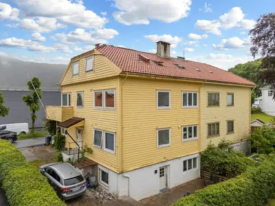 a yellow house with a car parked in front of it at King bed - Free parking - Renovated June 2025 in Bergen