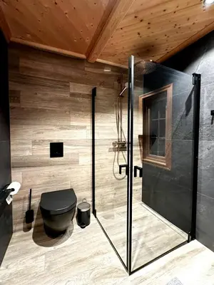 a bathroom with a black toilet and a wooden wall at Nature-Close Cabin By Trysil Mountain in Trysil