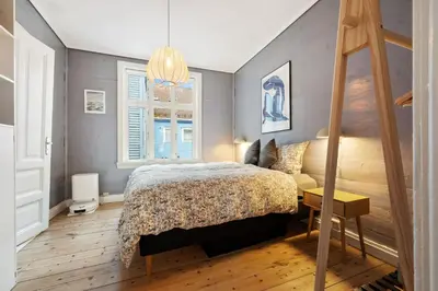 a bedroom with a bed and a desk and windows at Authentic Bergen Apartment in Bergen