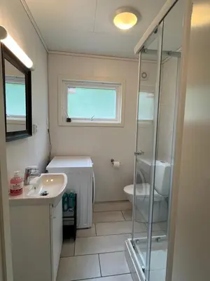 a bathroom with a glass shower and a sink at Green apartment in Odda
