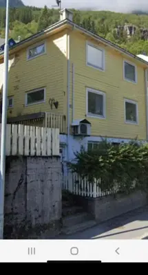 a yellow house with a fence in front of it at Green apartment in Odda