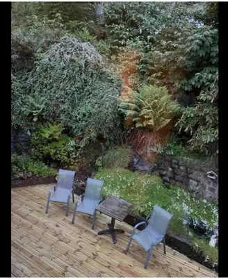 a patio with two chairs and a table and a garden at Green apartment in Odda