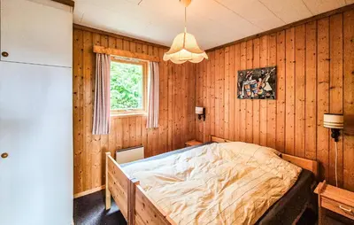 a bedroom with a bed in a wooden wall at Amazing Home In Frekhaug in Frekhaug