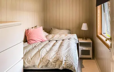 a bedroom with a bed with pink pillows at 3 Bedroom Amazing Home In Elnesvågen in Sylte