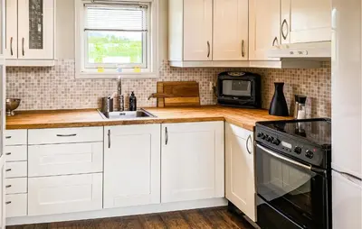 a kitchen with white cabinets and a sink and a microwave at 3 Bedroom Amazing Home In Elnesvågen in Sylte