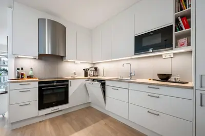 a white kitchen with white cabinets and a sink at Roomsly Apartments - City flat with Private Balcony in Bergen