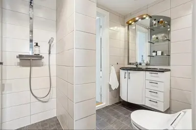 a white bathroom with a shower and a toilet at Downtown apartment with a view in Bergen