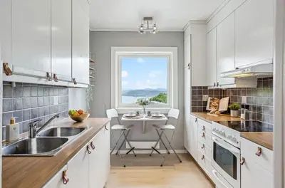 a kitchen with white cabinets and a sink and a window at Downtown apartment with a view in Bergen