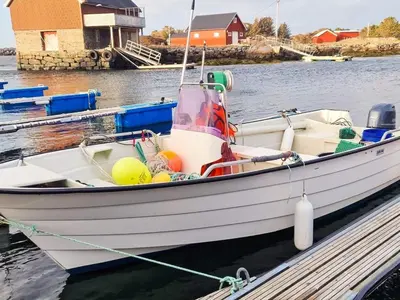 a white boat tied to a dock in the water at 8 person holiday home in Sandøy in Finnøy
