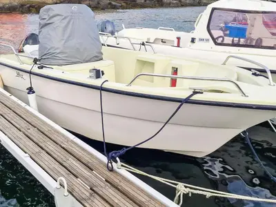 a white boat is docked at a dock at 8 person holiday home in Sandøy in Finnøy