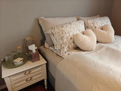 a bed with two heart pillows and a night stand at Bright & Spacious Apartment by the Sea, Free Parking, 10min to Airport, 12min to Ålesund in Ytterland