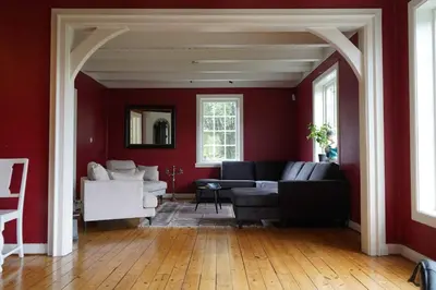 a living room with red walls and a black couch at Traditional Norwegian Villa, Bay view and boat in Bergen
