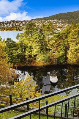 a boat is docked in a river next to a city at Traditional Norwegian Villa, Bay view and boat in Bergen