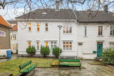 a white house with two green benches in front of it at Historic House City Centre in Bergen