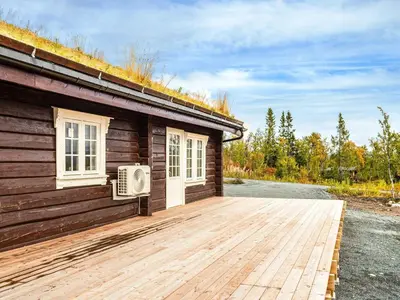 a cabin with a wooden deck next to a building at 8 person holiday home in Ålen in Ålen