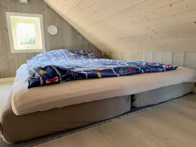 a bed in a room with a wooden ceiling at 4 star holiday home in Huglo in Nordhuglo