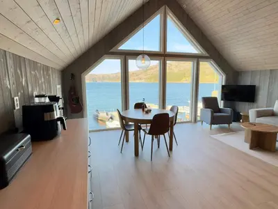 a living room with a table and a view of the water at 4 star holiday home in Huglo in Nordhuglo