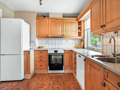 a kitchen with wooden cabinets and a white refrigerator at 8 person holiday home in Stavang in Stavang