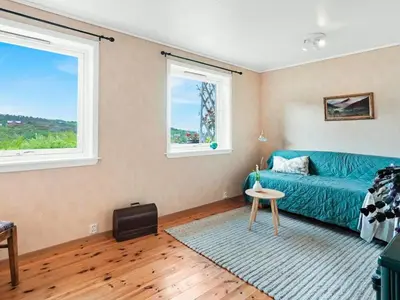 a living room with a blue couch and two windows at 8 person holiday home in Stavang in Stavang