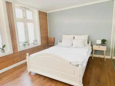 a white bed in a room with two windows at Cosy authentic apartment, only 60m from Bryggen! in Bergen