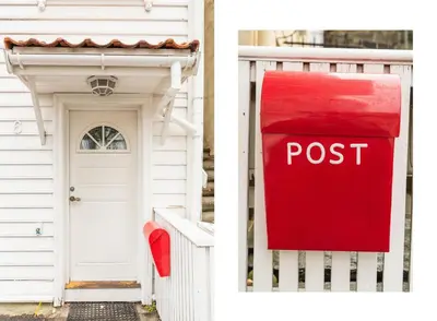 a red post sign in front of a white house at Cosy authentic apartment, only 60m from Bryggen! in Bergen