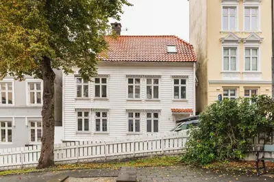 a white house with a white fence in front of it at Cosy authentic apartment, only 60m from Bryggen! in Bergen