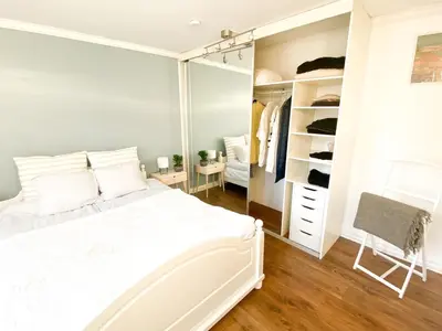 a bedroom with a large white bed and a mirror at Cosy authentic apartment, only 60m from Bryggen! in Bergen
