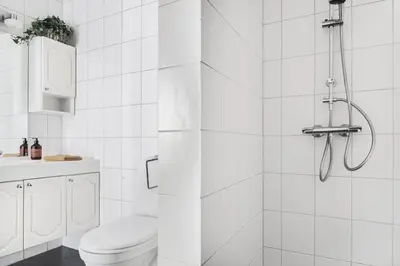 a white bathroom with a shower and a toilet at Cosy authentic apartment, only 60m from Bryggen! in Bergen
