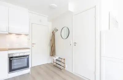 a white kitchen with white cabinets and a mirror at Modern apartment ONLY 5 minutes from City centre in Bergen