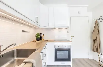a kitchen with white cabinets and a stainless steel sink at Modern apartment ONLY 5 minutes from City centre in Bergen